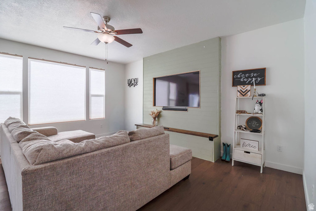 373 Quartz Road Tooele, UT 84074 - Photo 9 of 38 Wood-finish flooring throughout, ceiling fan with integrated lighting, multiple windows with blinds, and a built-in entertainment wall with a floating shelf