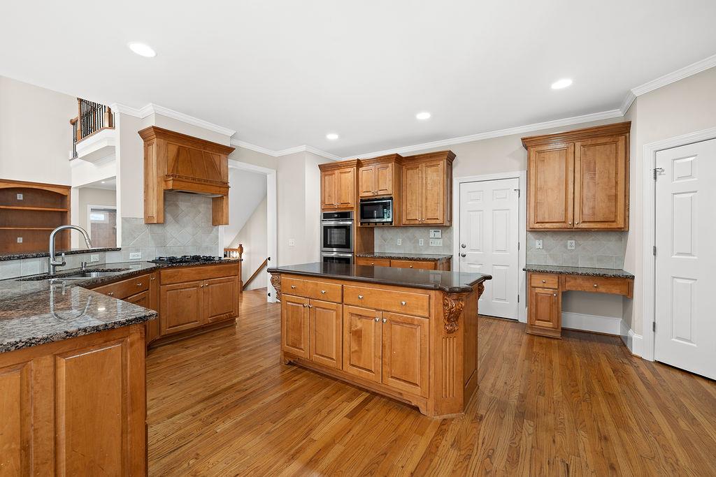 1037 Windermere Crossing Cumming, GA 30041 - Photo 20 of 95 a large kitchen with stainless steel appliances granite countertop wooden floors a sink and a granite counter tops