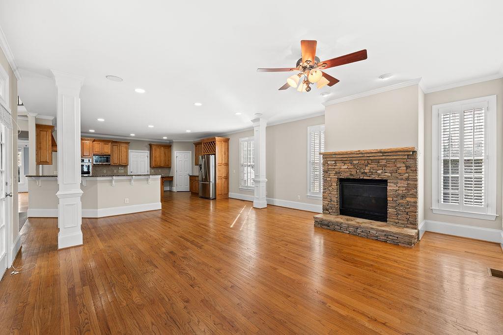 1037 Windermere Crossing Cumming, GA 30041 - Photo 26 of 95 a view of a livingroom with wooden floor a ceiling fan and kitchen view