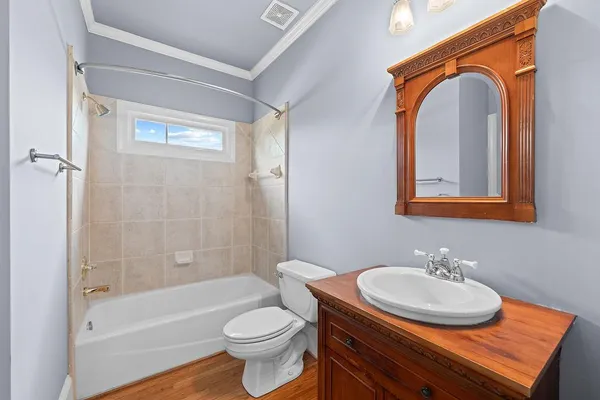 a bathroom with a bathtub shower sink vanity mirror and toilet