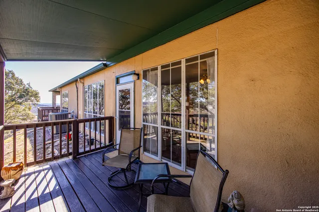 a balcony with wooden floor table and chairs
