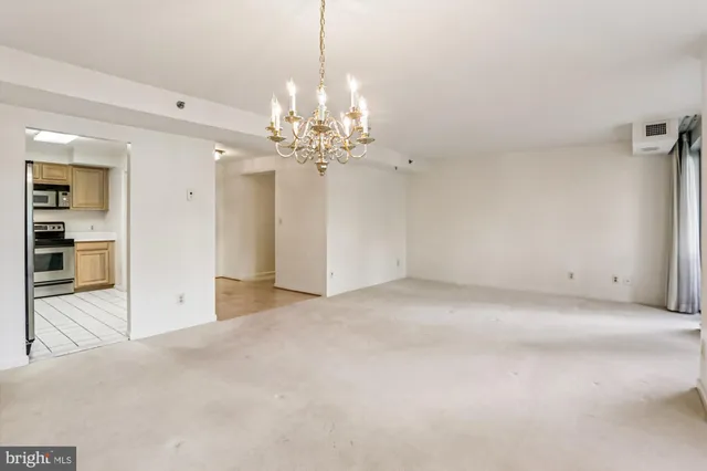a view of a livingroom with a chandelier fan and kitchen view