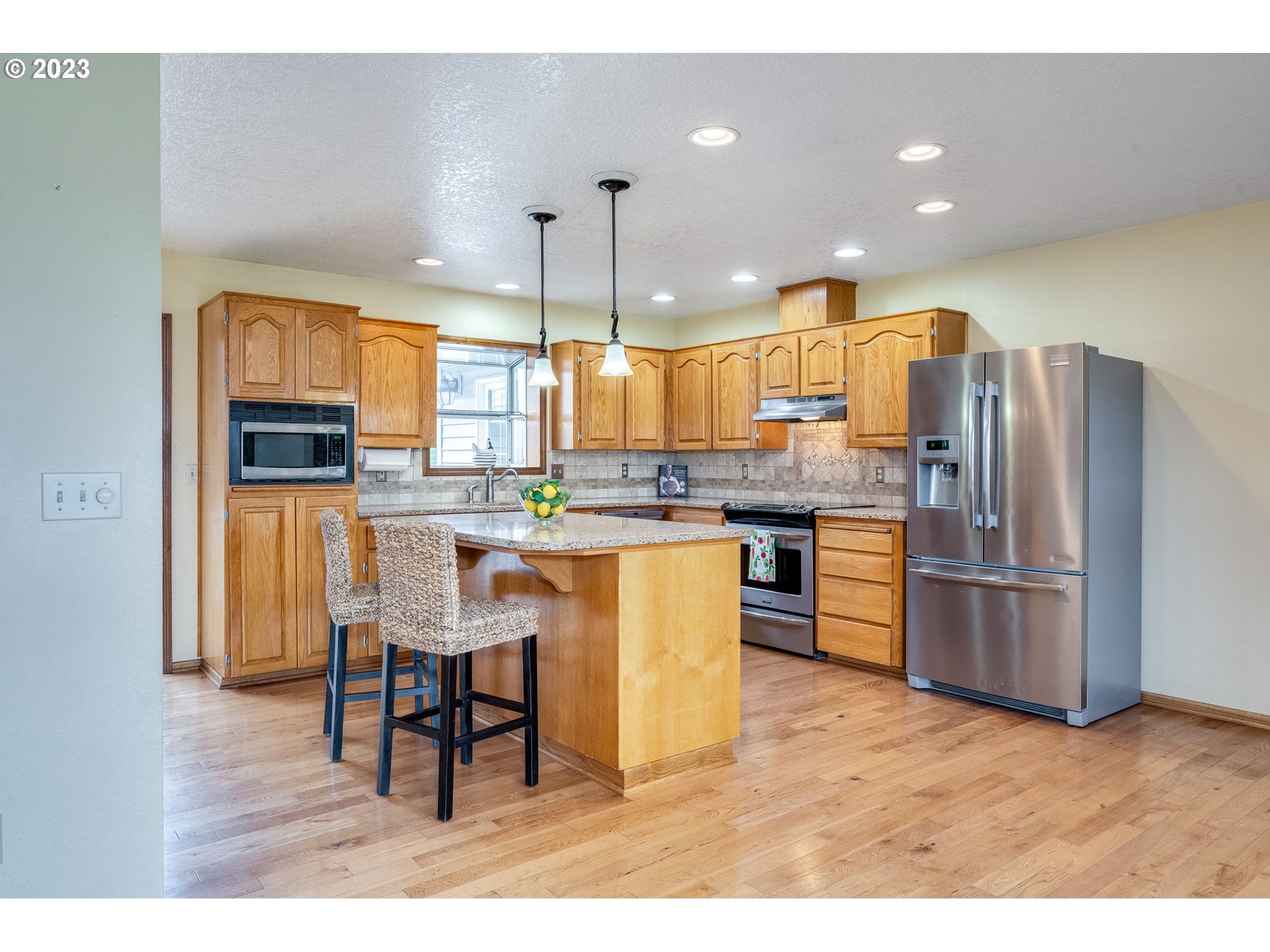 1740 North Laurelwood Loop Canby, OR 97013 - Photo 11 of 46 a kitchen with stainless steel appliances kitchen island granite countertop a refrigerator a stove a sink dishwasher with a dining table and chairs