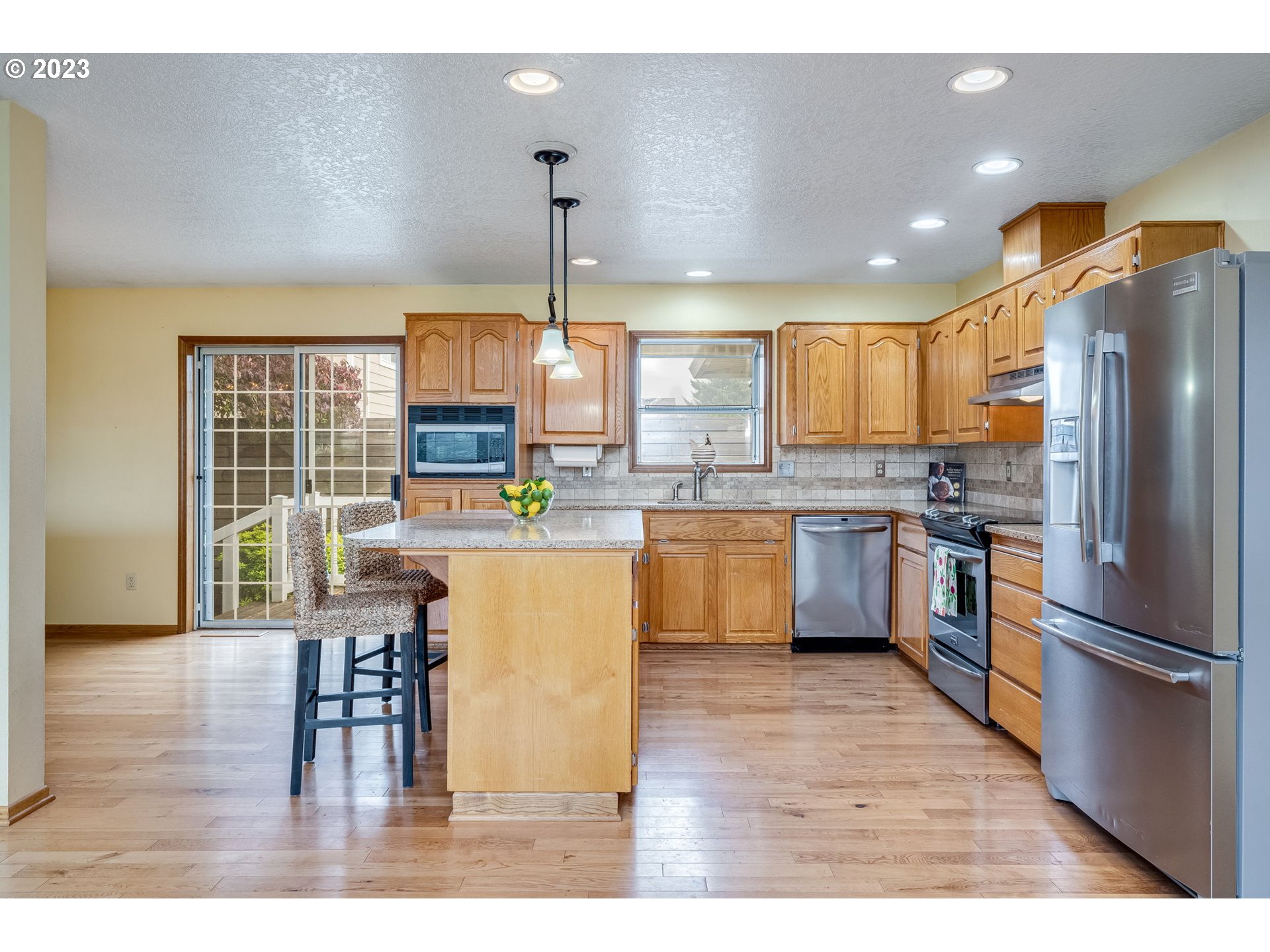 1740 North Laurelwood Loop Canby, OR 97013 - Photo 12 of 46 a kitchen with stainless steel appliances granite countertop a refrigerator a sink dishwasher a stove and a dining table with wooden floor
