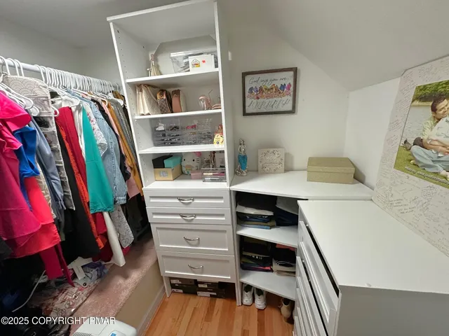 a view of walk in closet with clothes and shoes