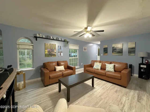 a living room with furniture ceiling fan and a window