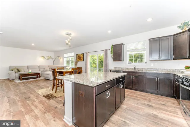 a kitchen with stainless steel appliances granite countertop a stove top oven a sink dishwasher a dining table and chairs with wooden floor