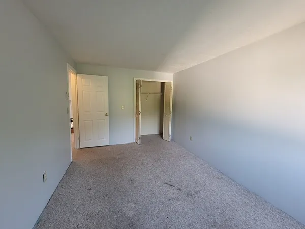 a view of an empty room with closet and wooden floor