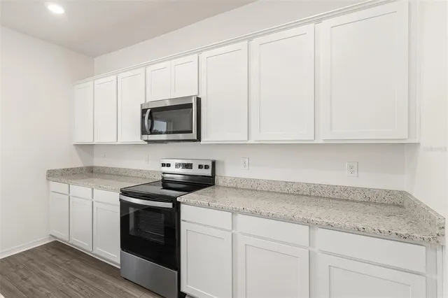 a kitchen with granite countertop white cabinets and white appliances