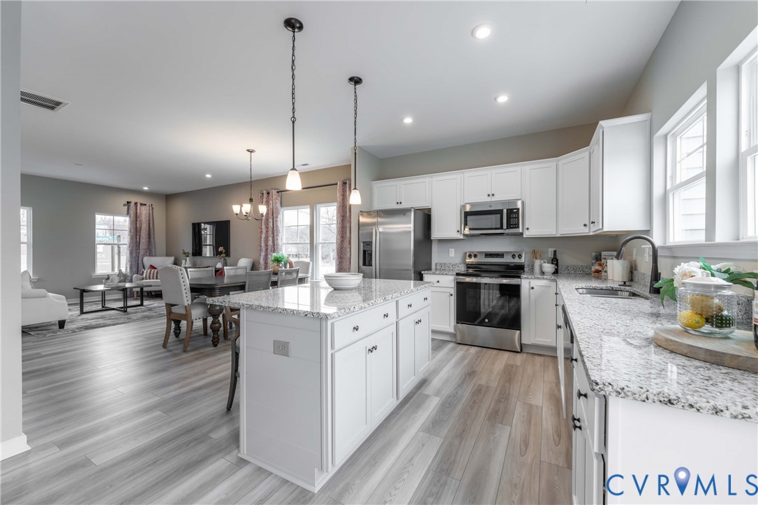3437 Broadwick Road Richmond, VA 23234 - Photo 8 of 24 a kitchen with stainless steel appliances granite countertop a refrigerator a stove top oven a sink a dining table and chairs with wooden floor