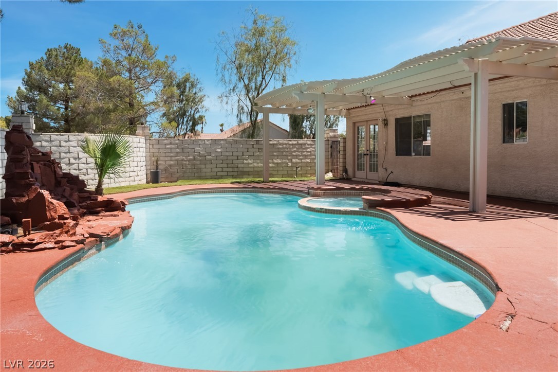 9028 Cypress Point Road Las Vegas, NV 89117 - Photo 34 of 39 A spacious backyard features a shimmering pool with a rock waterfall and a covered patio, perfect for outdoor enjoyment.