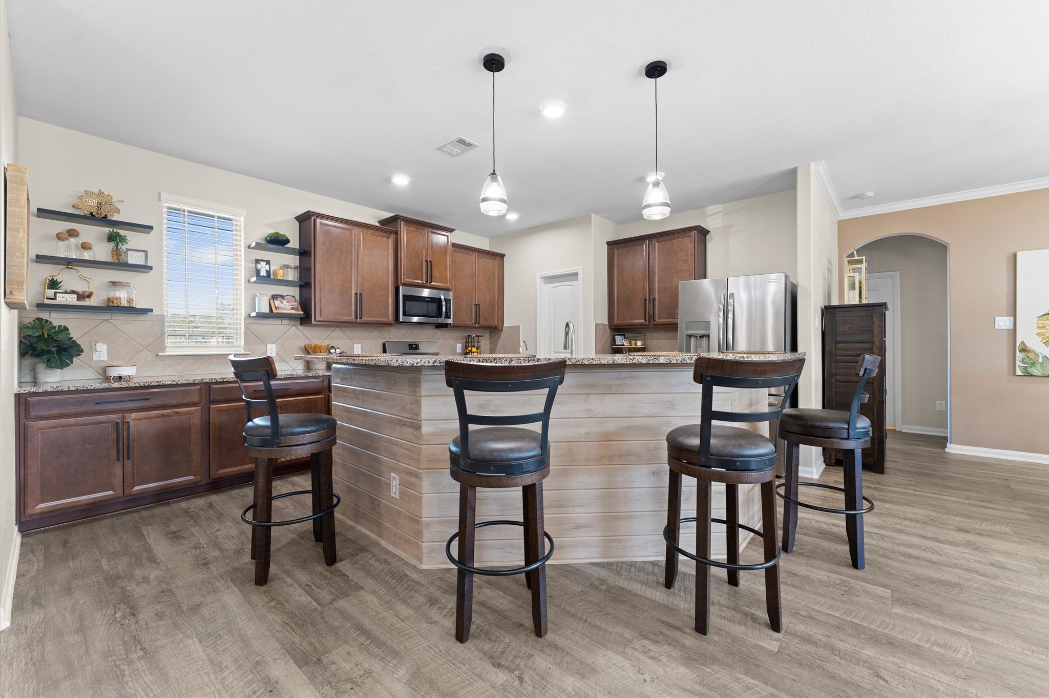 9729 Hidalgo Street Conroe, TX 77303 - Photo 15 of 38 This modern kitchen features an open layout with a central island, granite countertops, and bar seating. It includes stainless steel appliances, ample cabinet space, and stylish pendant lighting, creating a perfect blend of functionality and elegance.