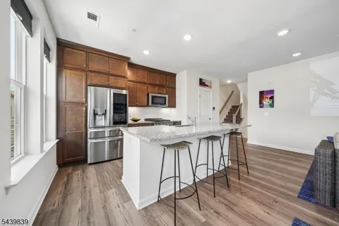 a kitchen with stainless steel appliances a dining table chairs and wooden floor