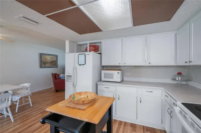 a kitchen with stainless steel appliances kitchen island granite countertop a table chairs and a refrigerator