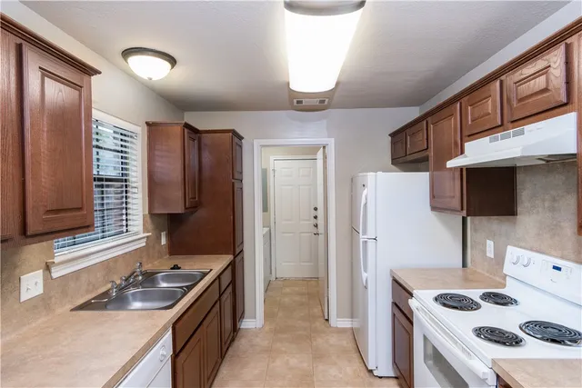 a kitchen that has a sink a refrigerator and a stove