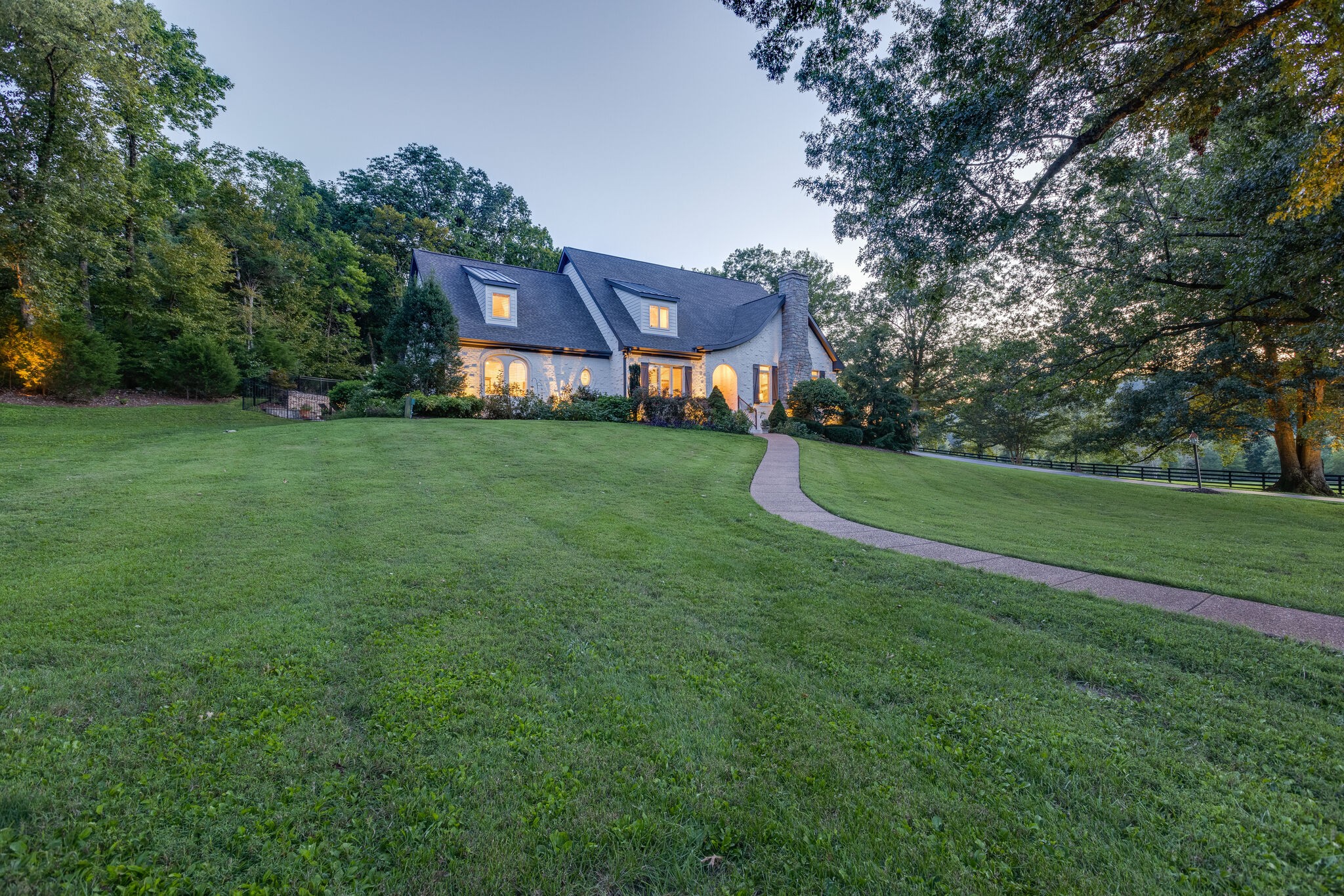 a view of a house next to a big yard and large trees