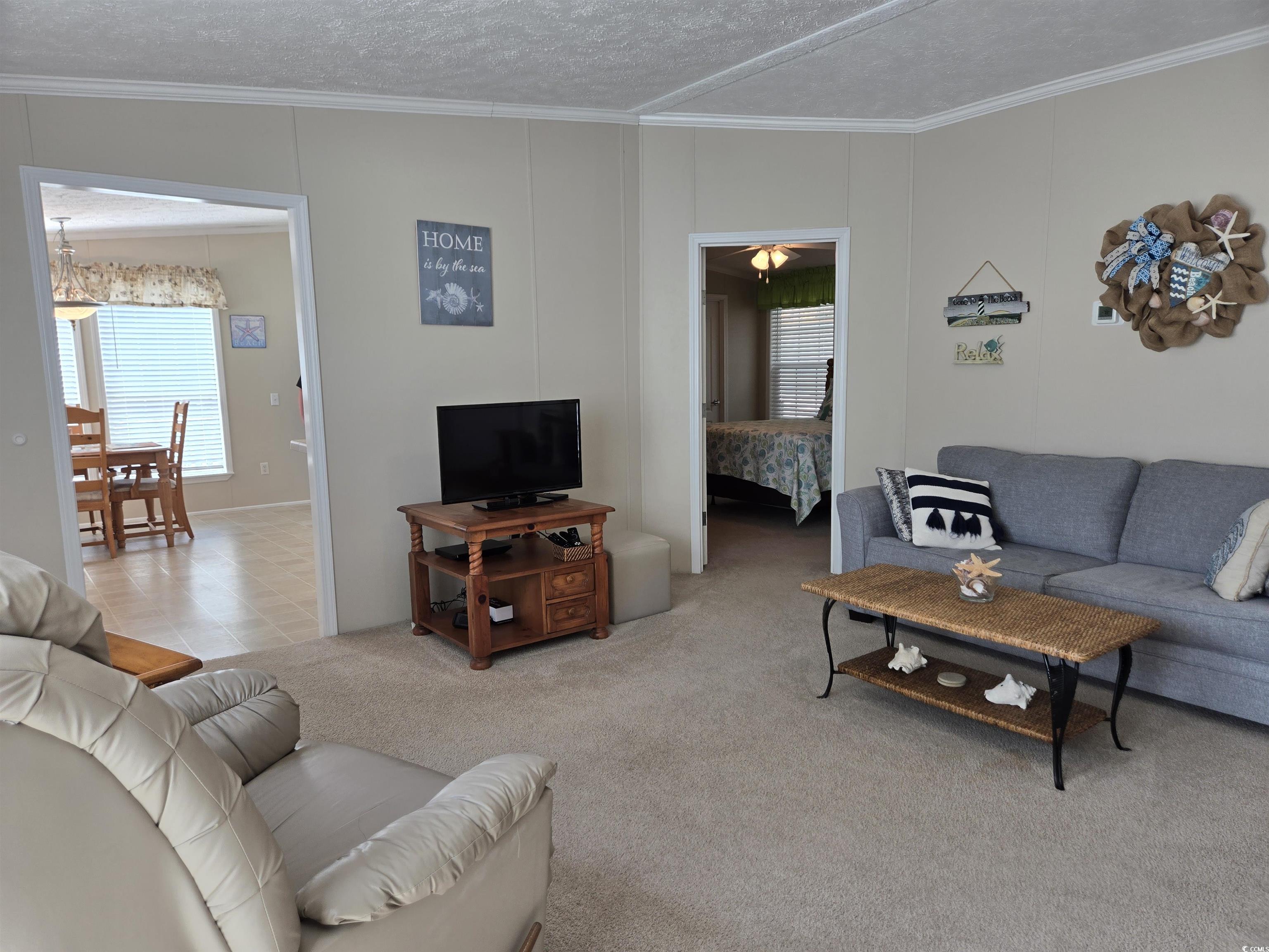337 Clam Shell Circle Murrells Inlet, SC 29576 - Photo 11 of 29 Living room featuring crown molding, a textured ceiling, and carpet flooring