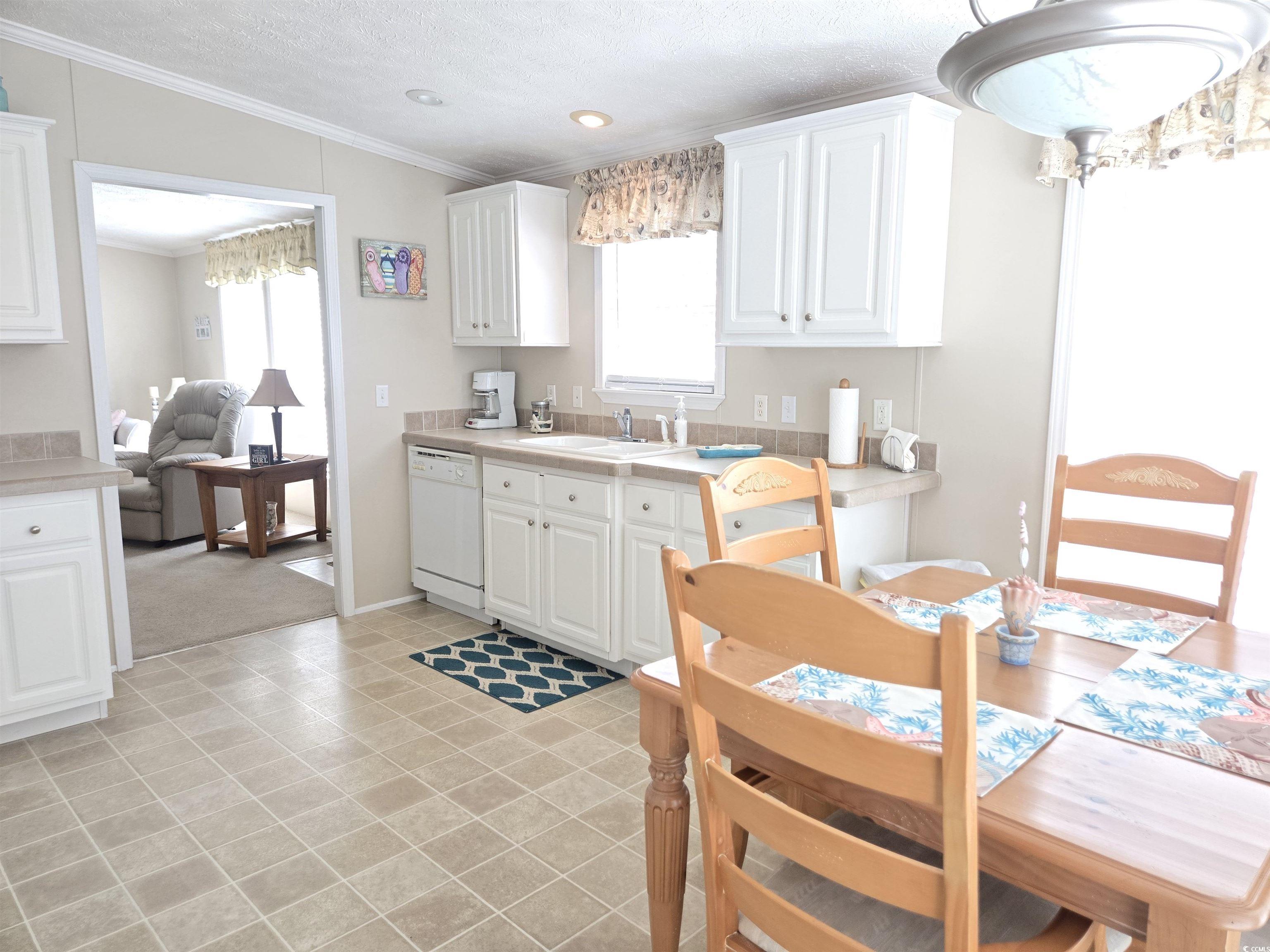 337 Clam Shell Circle Murrells Inlet, SC 29576 - Photo 12 of 29 Kitchen with crown molding, light countertops, dishwasher, white cabinetry, and a textured ceiling