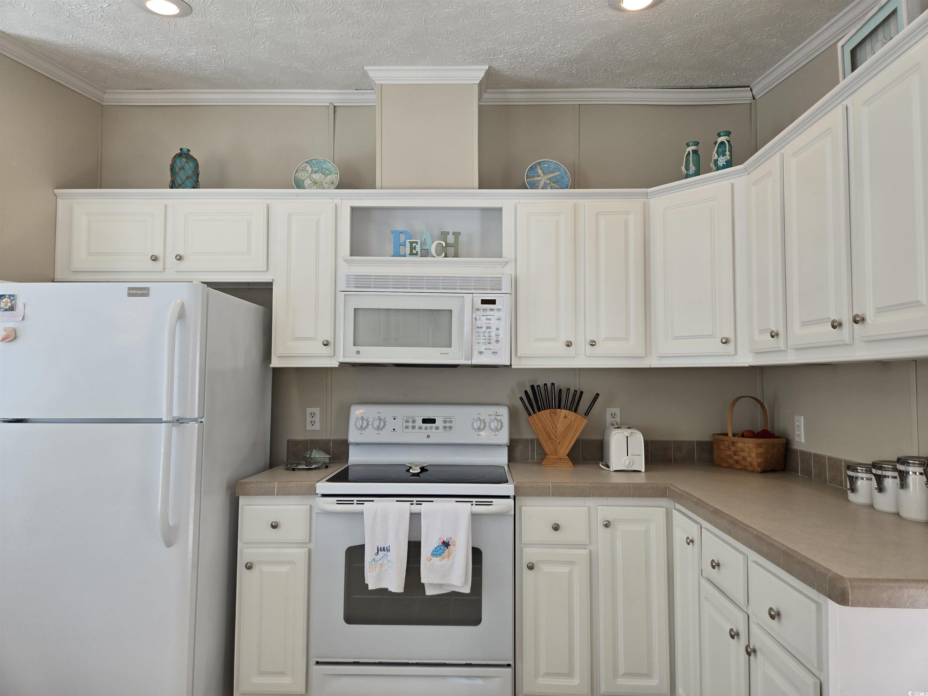337 Clam Shell Circle Murrells Inlet, SC 29576 - Photo 13 of 29 Kitchen featuring white appliances, white cabinets, open shelves, a textured ceiling, and light countertops