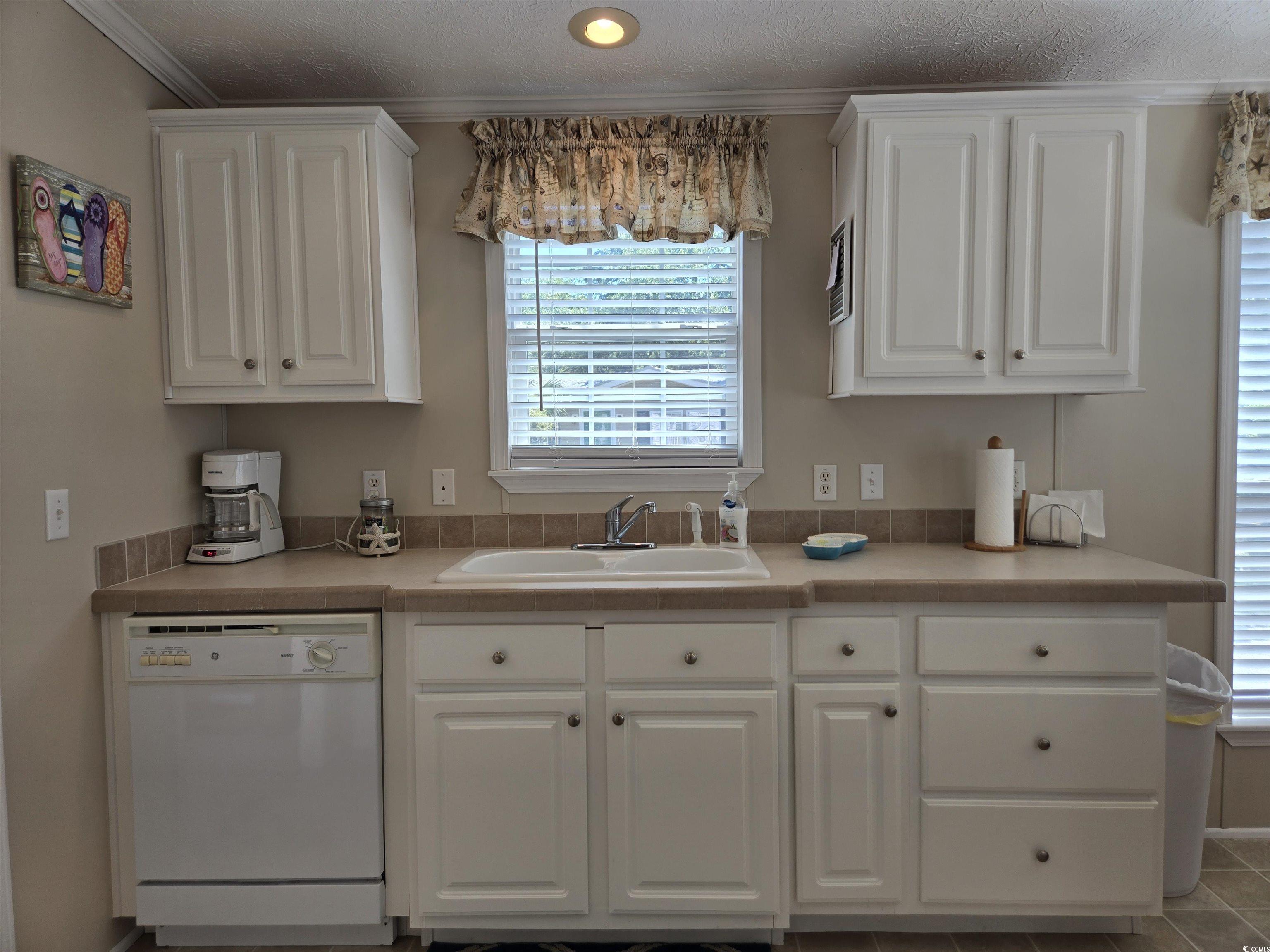 337 Clam Shell Circle Murrells Inlet, SC 29576 - Photo 14 of 29 Kitchen featuring white dishwasher, white cabinets, light countertops, ornamental molding, and a textured ceiling