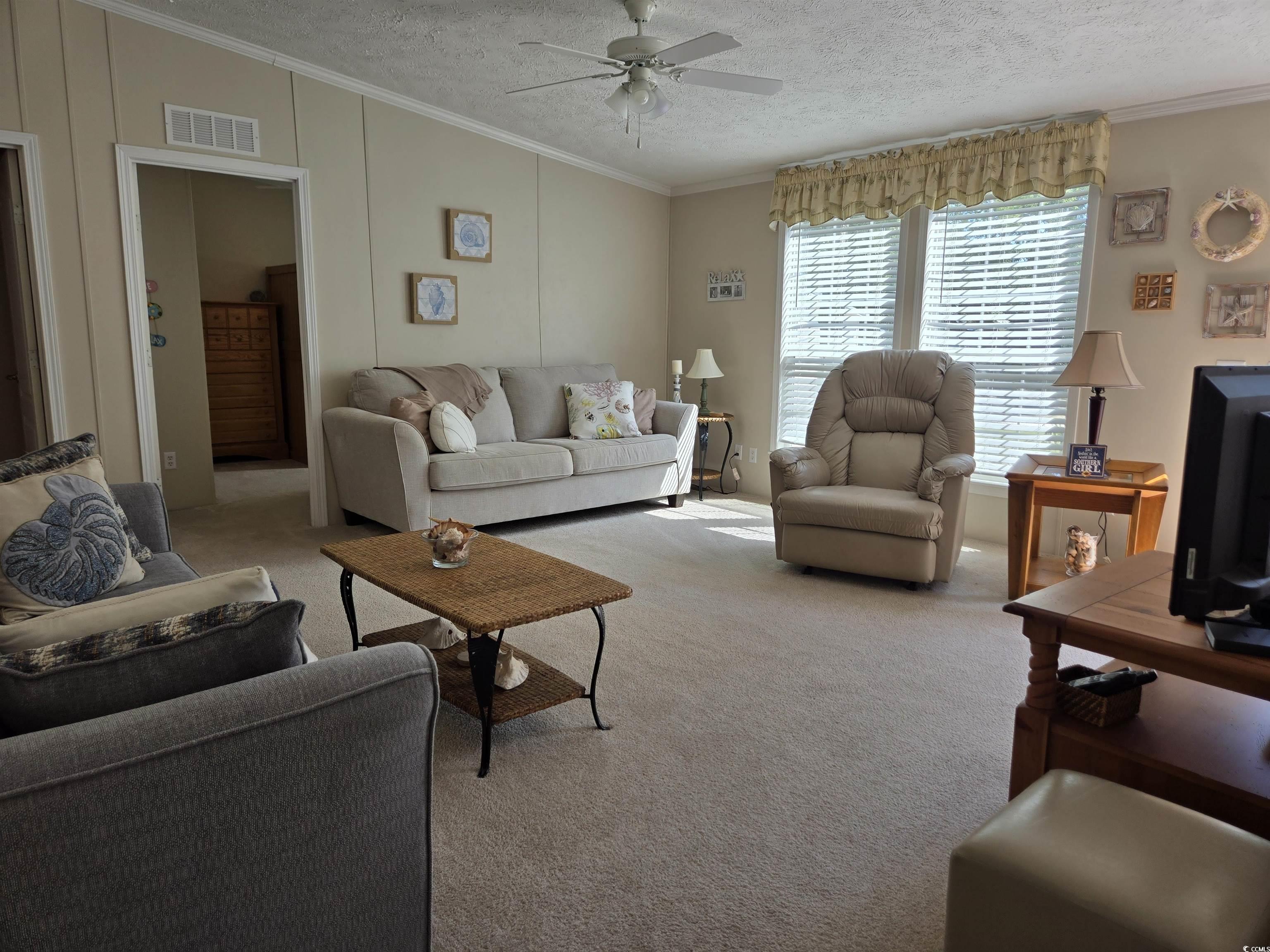 337 Clam Shell Circle Murrells Inlet, SC 29576 - Photo 9 of 29 Living room with ceiling fan, carpet floors, crown molding, and a textured ceiling