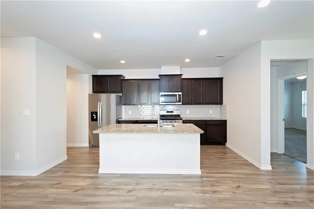 a large kitchen with stainless steel appliances kitchen island a large counter top and a wooden floors