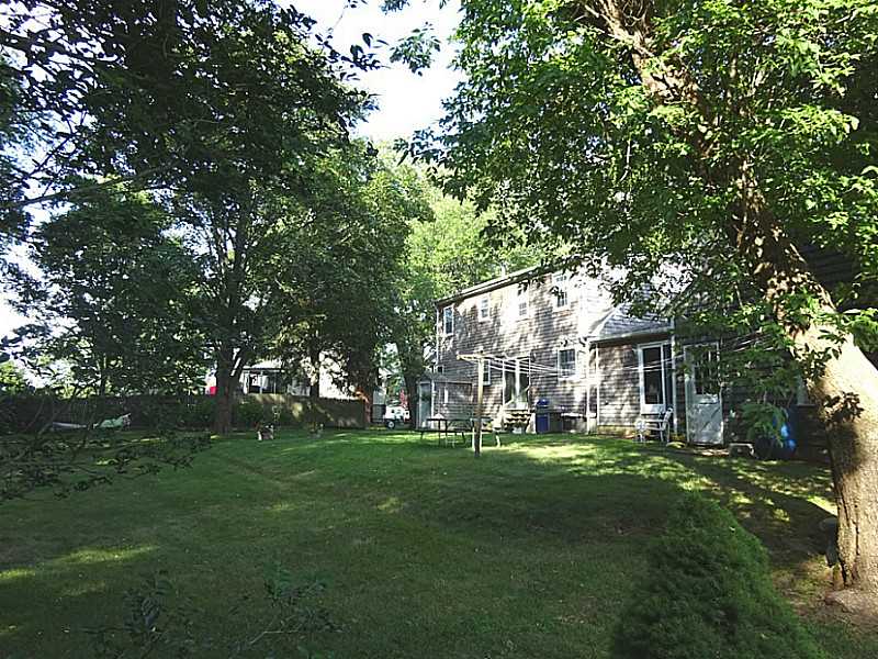 48 Pleasant Street Portsmouth, RI 02871 - Photo 3 of 25 Exterior Back. The lot is approx. 18000 square ft. The west side is bordered by a stone wall, north side has a wood stockade privacy fence and the south side is bordered by mature trees.