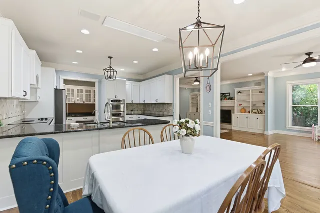 a kitchen with stainless steel appliances granite countertop a sink a stove a refrigerator a dining table and chairs