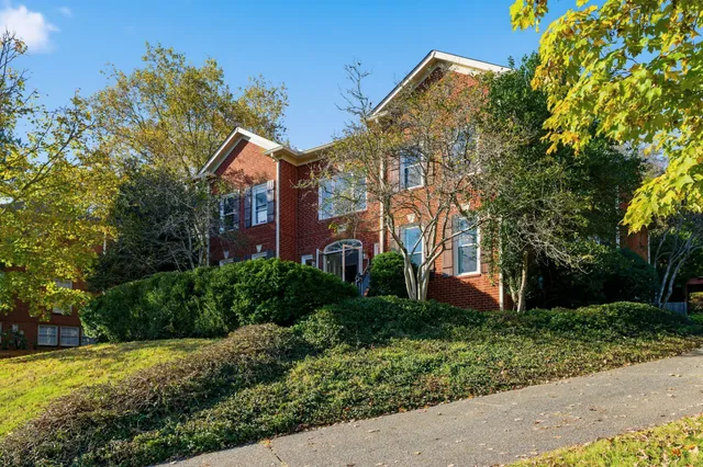 a front view of a house with a yard and tree s