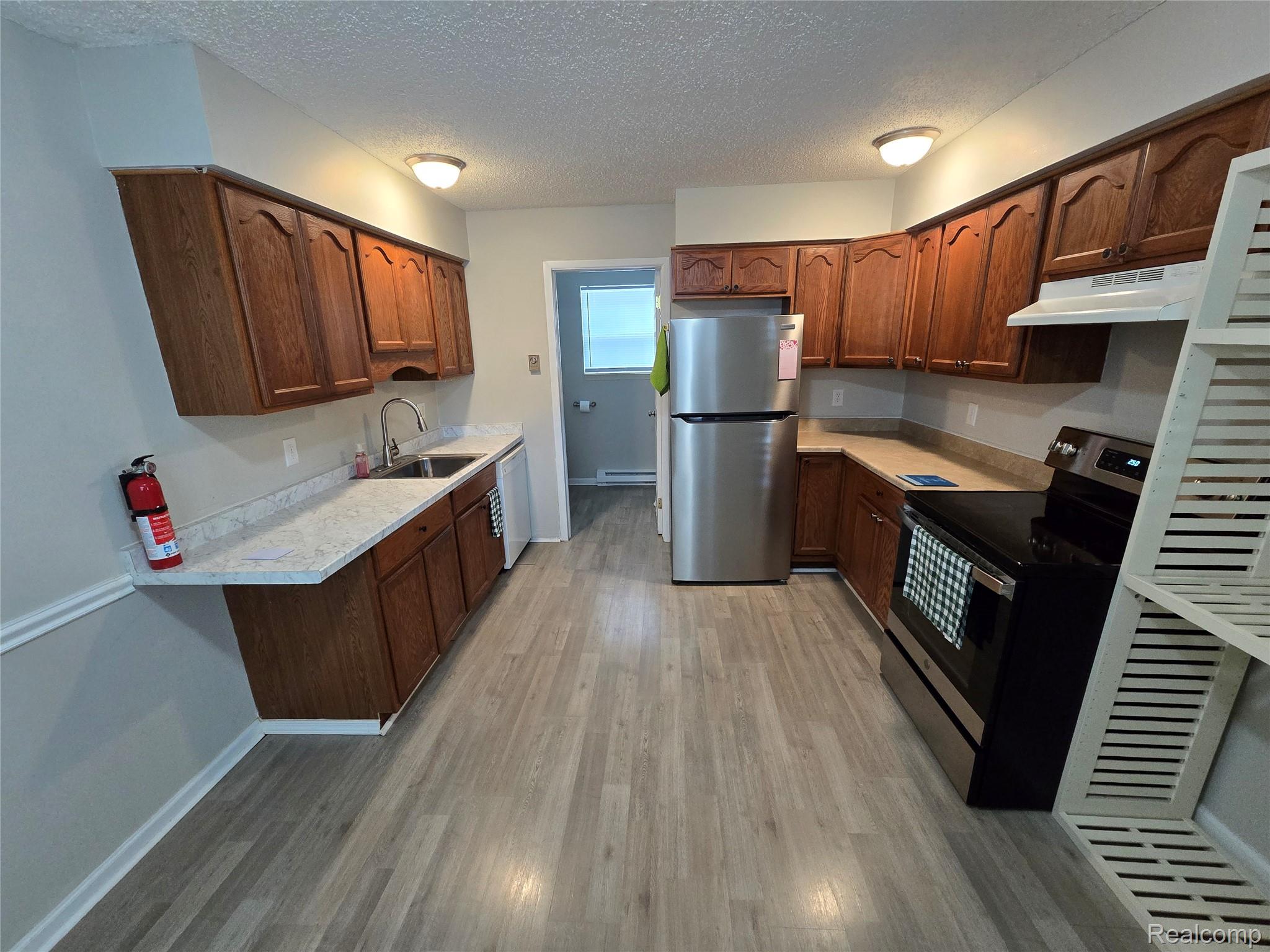 27780 Reo Road Grosse Ile, MI 48138 - Photo 2 of 18 Functional kitchen featuring wood-finish cabinetry, light-colored countertops, stainless steel appliances, and wood-look flooring