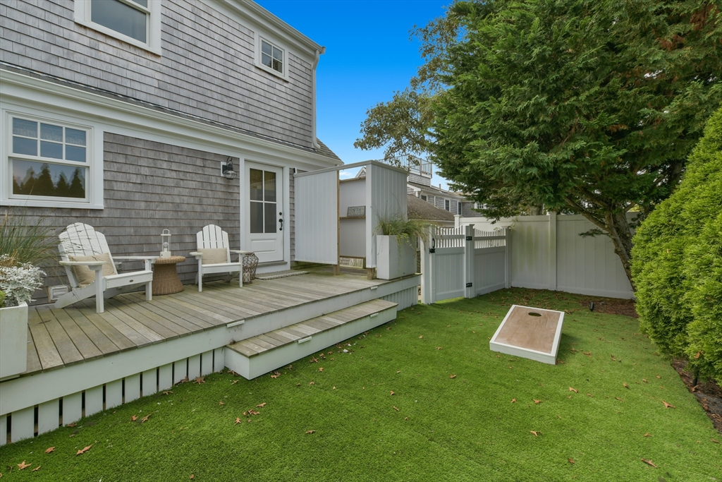 8 Port Pines Road Harwich Port, MA 02646 - Photo 35 of 42 a view of a backyard with table and chairs and a barbeque with potted plants