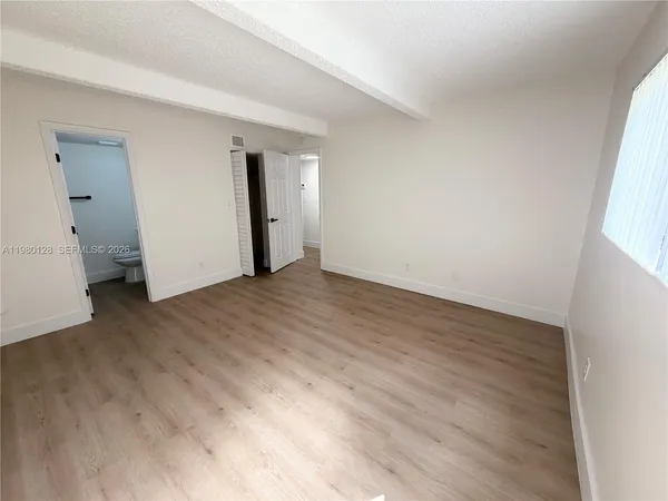 an empty room with wooden floor and mirror