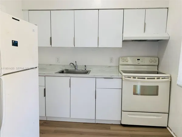 a kitchen with granite countertop white cabinets and white appliances