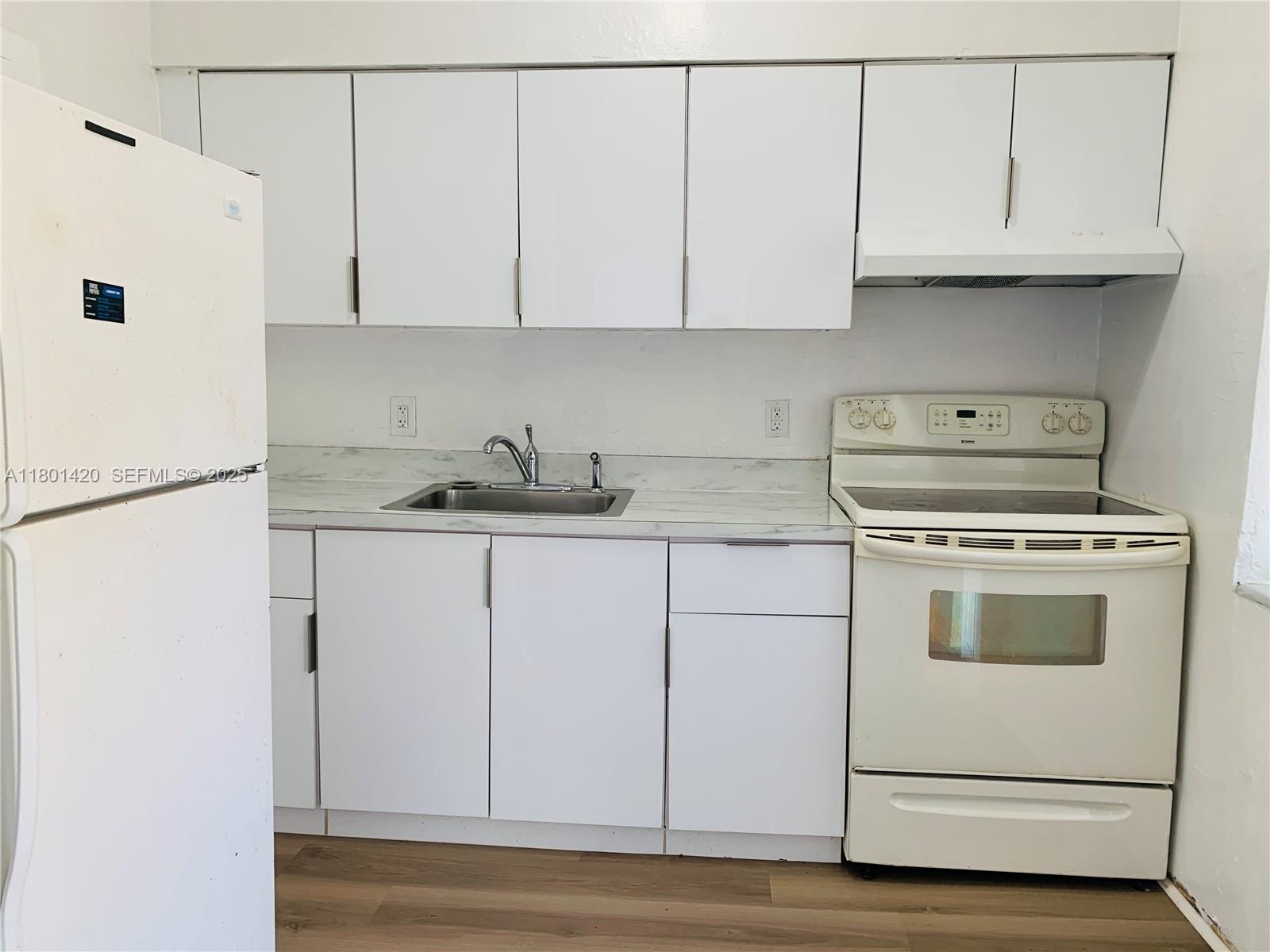 a kitchen with granite countertop white cabinets and white appliances