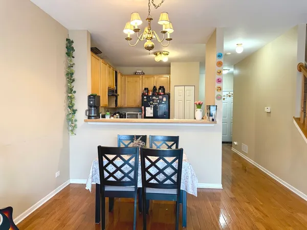 a dining room with wooden floor a chandelier a wooden table and chairs