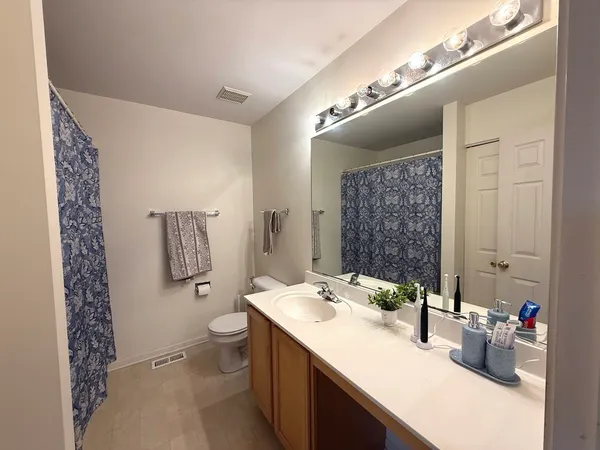a bathroom with a granite countertop sink a toilet a mirror and shower