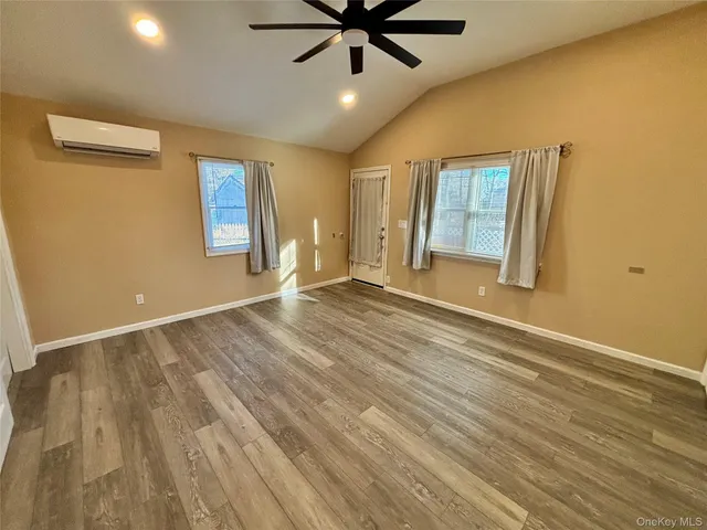 a view of an empty room with window and wooden floor