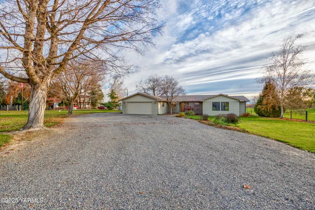 a front view of a house with a yard and large trees