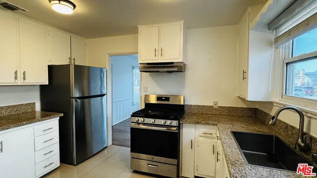 a kitchen with granite countertop a refrigerator stove and sink