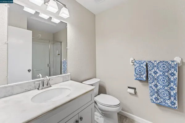 a bathroom with a granite countertop toilet a sink and a mirror