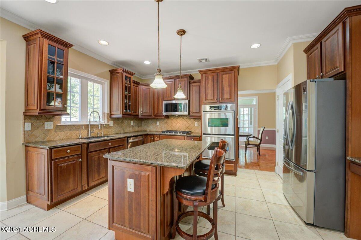 26 Emily Road Manalapan, NJ 07726 - Photo 13 of 49 a kitchen with stainless steel appliances granite countertop a stove a refrigerator a sink a dining table and chairs with wooden floor