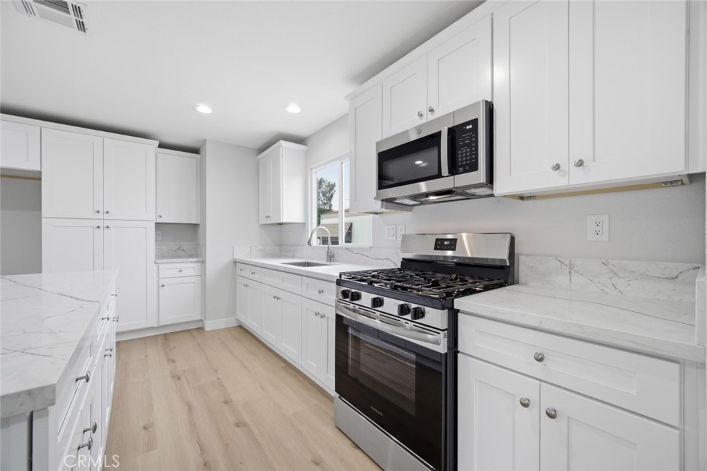 27615 Harrison Avenue Menifee, CA 92585 - Photo 8 of 18 a kitchen with stainless steel appliances granite countertop a stove a sink and a microwave