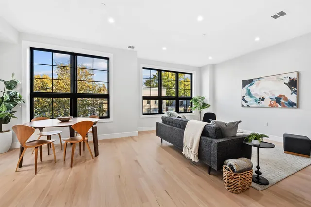 a living room with furniture a wooden floor and next to a window