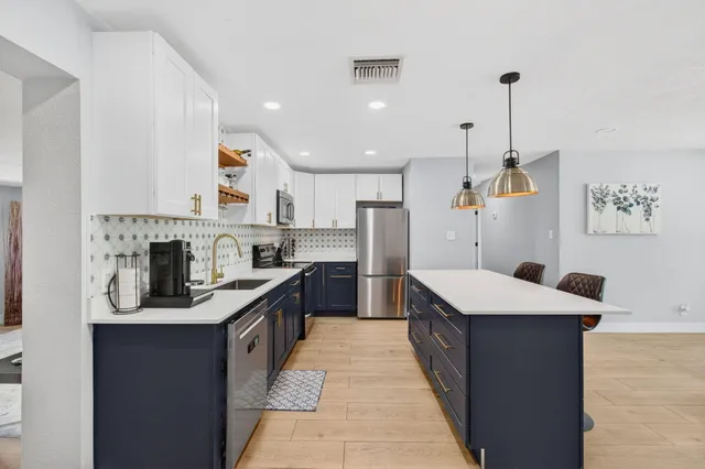 a kitchen with stainless steel appliances granite countertop a sink a stove and a refrigerator