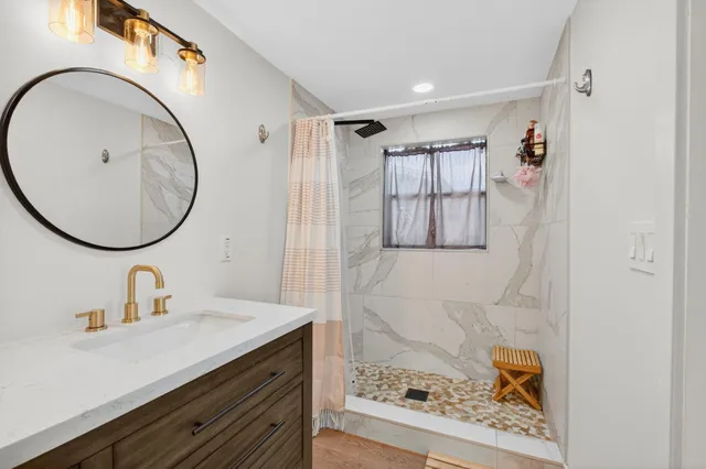 a bathroom with a sink a mirror a vanity and a shower