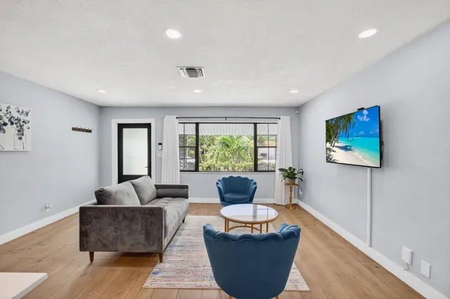 a living room with furniture a large window and a wooden floor