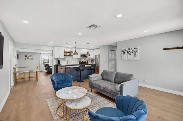 a living room with furniture kitchen view and a wooden floor