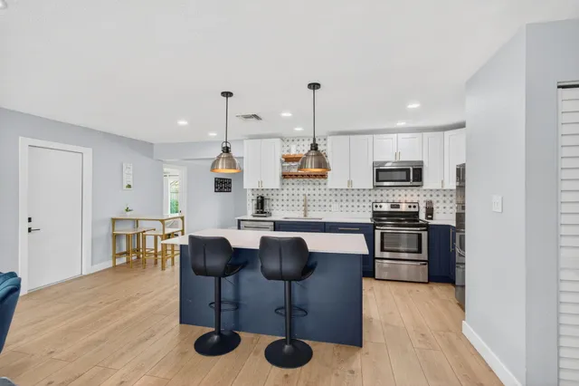 a kitchen with stainless steel appliances kitchen island granite countertop a table chairs stove and white cabinets