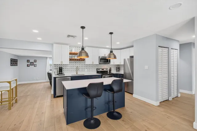 a kitchen with stainless steel appliances kitchen island granite countertop a table chairs stove and microwave