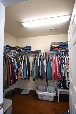 a walk in closet with clothes and shoes